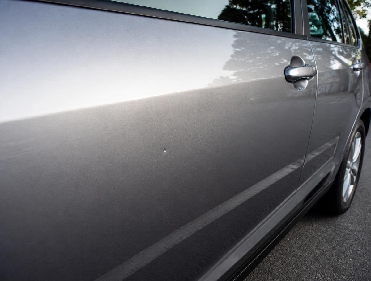 Shallow ding on the rear door of a grey vehicle