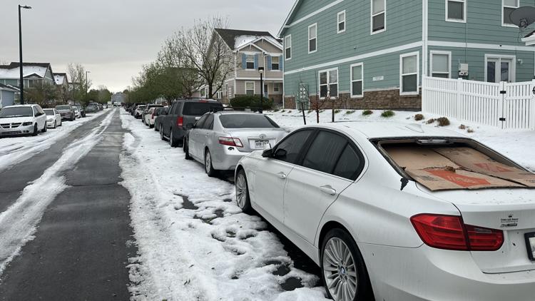 Hail-covered Denver neighborhood street with damaged vehicles parked after a Colorado hail storm