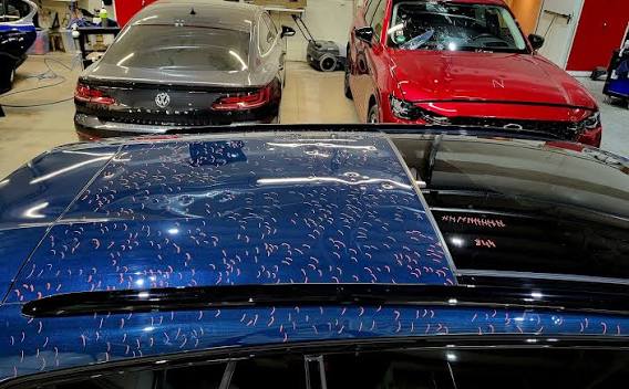 Hail dents marked across the roof of a blue vehicle inside the Denver paintless dent repair shop