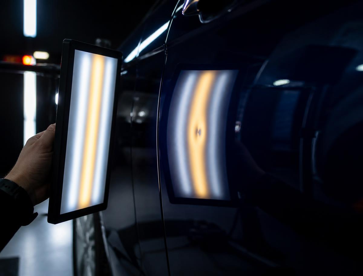 Technician inspecting a panel for small dents